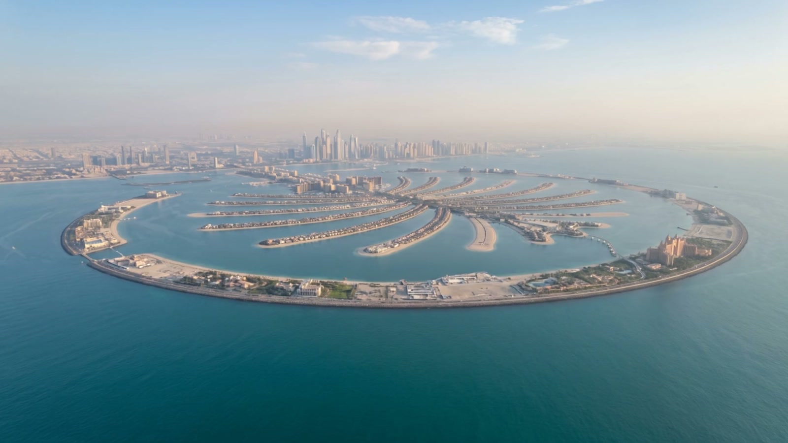 The Dubai skyline at first light, seen across calm water under an open sky
