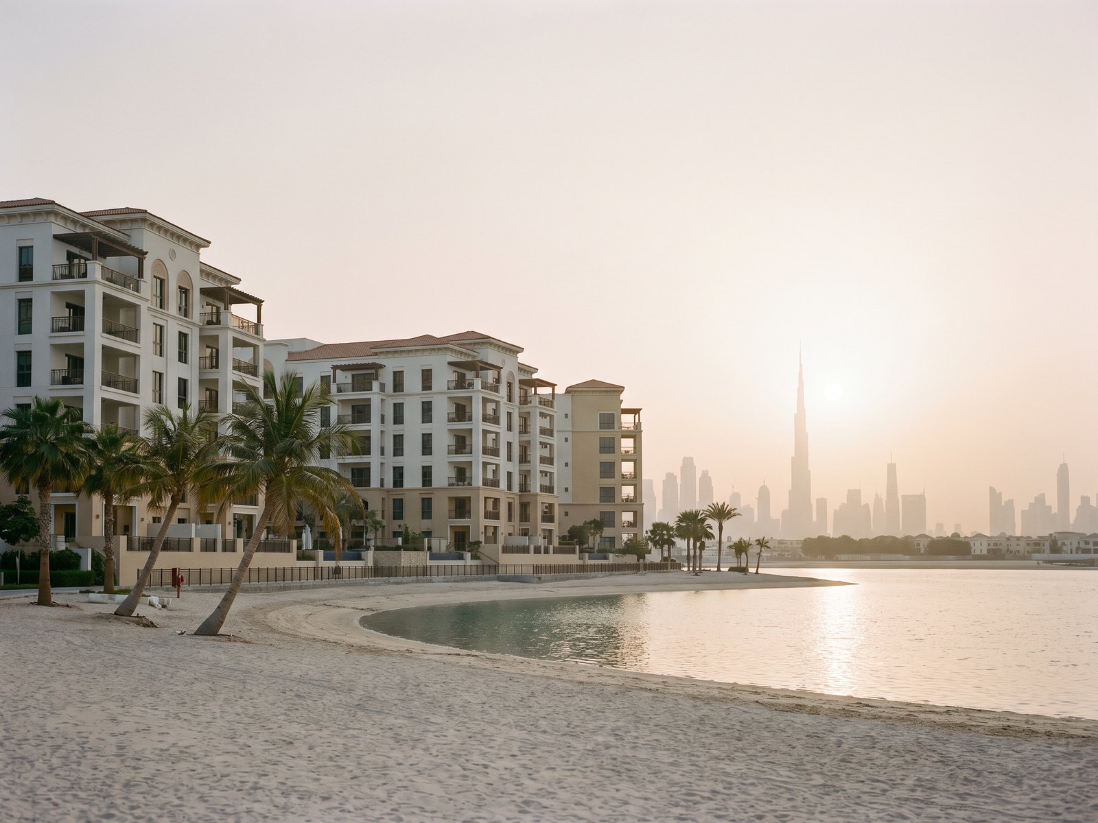 Impression of Bayshore at Creek Beach: low-rise white and sand buildings facing the lagoon beach with the Downtown skyline across the water